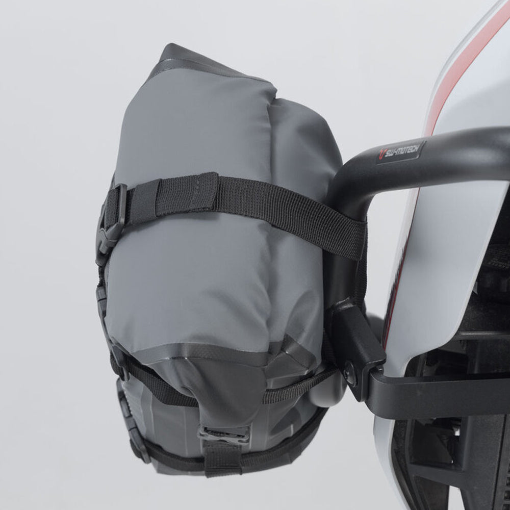 Gray bag attached to a bicycle handlebar against a plain background.